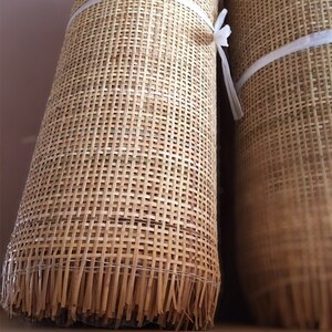 Rolls of natural square woven cane webbing. The webbing is a light brown color and has a woven pattern.