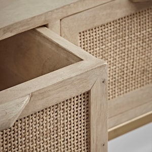Pu&ograve; includere: Primo piano di un mobile in legno chiaro con due cassetti. I cassetti hanno frontali in canna intrecciata.