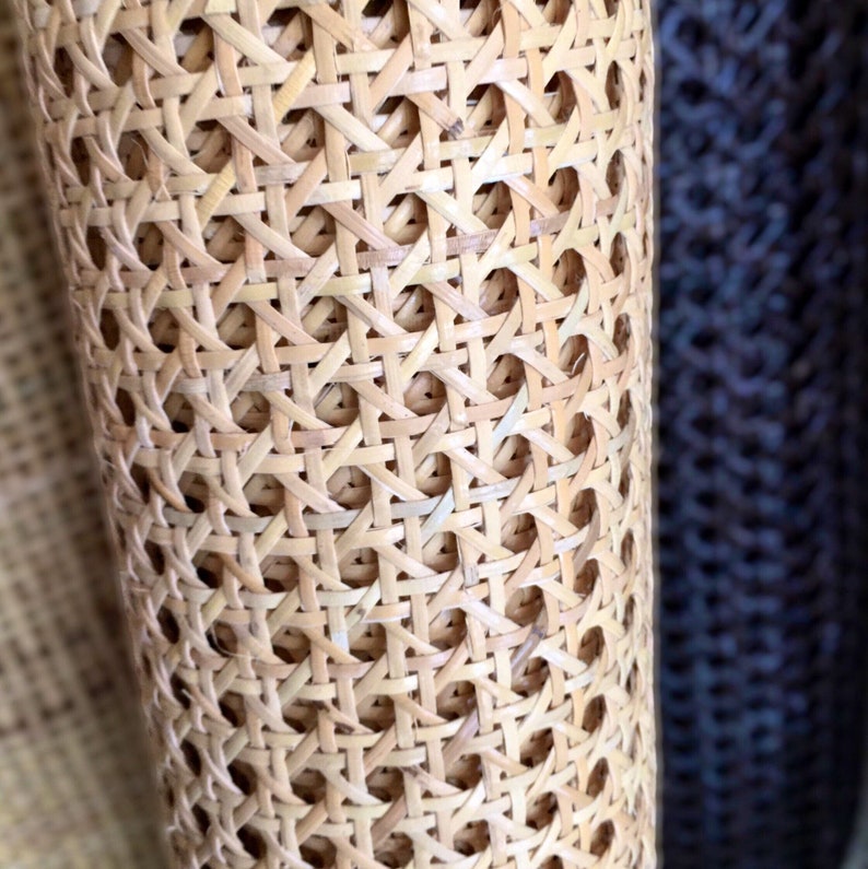 May include: Close-up of a woven cane material, often used for chair seats and other furniture. The material is light brown and has a tight weave.