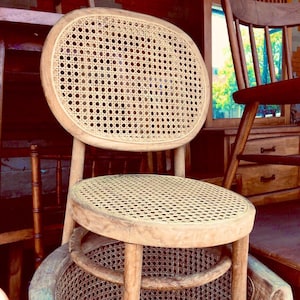 May include: A wooden chair with a woven cane seat and back. The chair has a rounded back and a simple design.
