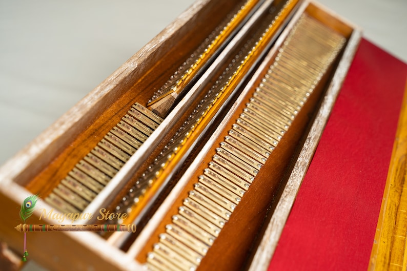 May include: Close-up of a wooden box containing numerous small, rectangular, brass-coloured pieces. The box has a natural wood finish and a red fabric lining. The image is well-lit, highlighting the details.
