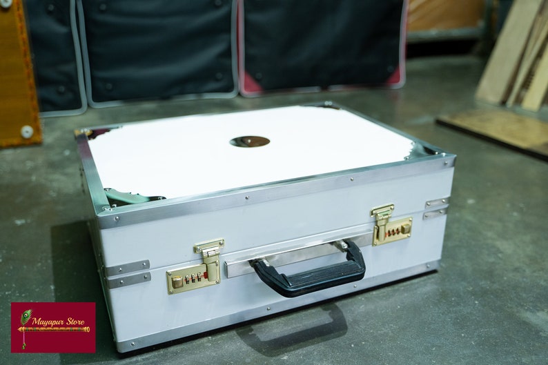 May include: A white, rectangular, hard-sided case with a silver trim and a black handle. The case has two locks with combination dials and a white interior.