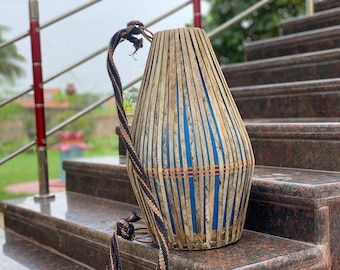 Könnte beinhalten: Eine traditionelle indische Trommel namens Tabla, aus Holz und Leder gefertigt, mit einem blau-braunen Streifenmuster. Die Trommel liegt auf einer Treppe.