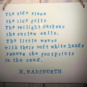 May include: A rectangular, off-white ceramic plaque with a poem in blue text. The poem, titled "The tide rises," is printed in a typewriter font. The plaque has a jute rope for hanging and is suitable for home decor.