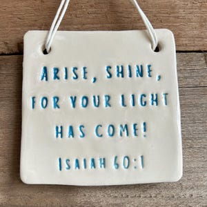 Puede incluir: Placa de cerámica blanca con texto azul que dice "Arise, Shine, For Your Light Has Come! Isaiah 60:1".
