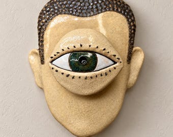Een keramisch wandmasker met één oog, surrealistische gezichtssculptuur, conceptuele kunstdecoratie