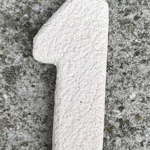 Op de afbeelding: Een set van drie keramische mokken met een gespikkelde, matte afwerking. De mokken zijn in de kleuren cr&egrave;me, lichtgrijs en donkergrijs. Elke mok heeft een eenvoudig, minimalistisch ontwerp en een afgeronde handgreep.