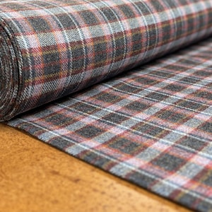 May include: A roll of gray plaid fabric with red, white, and yellow stripes. The fabric is woven with a textured finish.