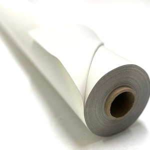 Op de afbeelding: Een rol wit papier is strak opgerold, met het uiteinde van de rol omgeslagen. Het papier is glad en heeft een lichte glans.