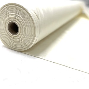 Puede incluir: Un rollo de tela blanca, desenrollado y colocado sobre una superficie blanca.