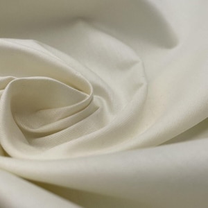 May include: Close-up of off-white fabric with soft folds and a subtle sheen. The material is tightly woven, suggesting a smooth texture. The fabric's color is a creamy, neutral tone, ideal for various sewing projects.