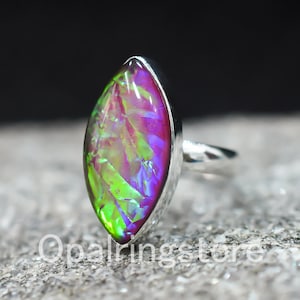 May include: A silver ring with a marquise-shaped iridescent opal gemstone. The opal has a green, pink, and purple color.