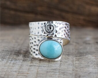 Può includere: Un anello d'argento con una pietra ovale blu chiaro e un design a spirale sulla fascia.