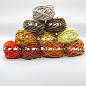 May include: A collection of 10 balls of cotton rope in various shades of brown, yellow, and orange. The balls are labeled with the colors: Natural, Sand, Mocha, Ochre, Sunflower, Yellow, Copper, Butterscotch, Foliage, and Pumpkin.