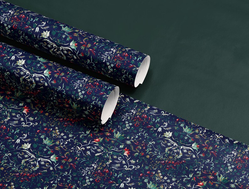 K&ouml;nnte beinhalten: Rollen von marineblauem Tapetenpapier mit floralem Muster und roten, gr&uuml;nen und wei&szlig;en Akzenten. Die Tapete ist auf einer dunkelgr&uuml;nen Oberfl&auml;che ausgerollt und zeigt das komplizierte Design. Die Rollen sind teilweise ausgerollt und zeigen die wei&szlig;e R&uuml;ckseite.