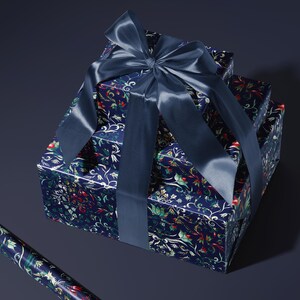 K&ouml;nnte beinhalten: Drei gestapelte Geschenkboxen, verpackt in marineblauem Papier mit einem floralen Muster in Rot, Gr&uuml;n und Wei&szlig;. Eine gro&szlig;e marineblaue Satinschleife ist oben gebunden. Eine Rolle passenden Geschenkpapieres ist zu sehen.