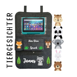 May include: Gray felt car seat organizer with pockets for a tablet, toys, and other items. It features a personalized name "Jonas" and the text "Hier Dein Spruch" (Here's your saying). The organizer is decorated with various animal illustrations, including a fox, deer, koala, rabbit, bear, and raccoon.