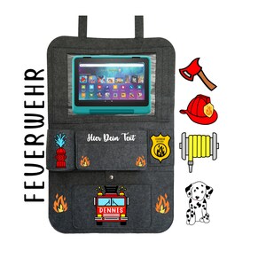 May include: A gray felt car seat organizer with a fire truck theme. It has a clear pocket for a tablet, a pocket with a fire hydrant, a pocket with a fire truck, and a pocket with a fire hose. The text "Hier Dein Text" is embroidered on the organizer.