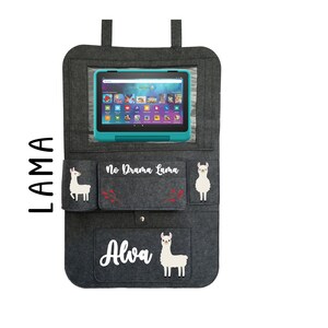 May include: Gray felt car seat organizer with a clear plastic window for a tablet. It has two pockets on the sides and a larger pocket on the bottom. The organizer has a llama design with the text "No Drama Llama" and "Alva".