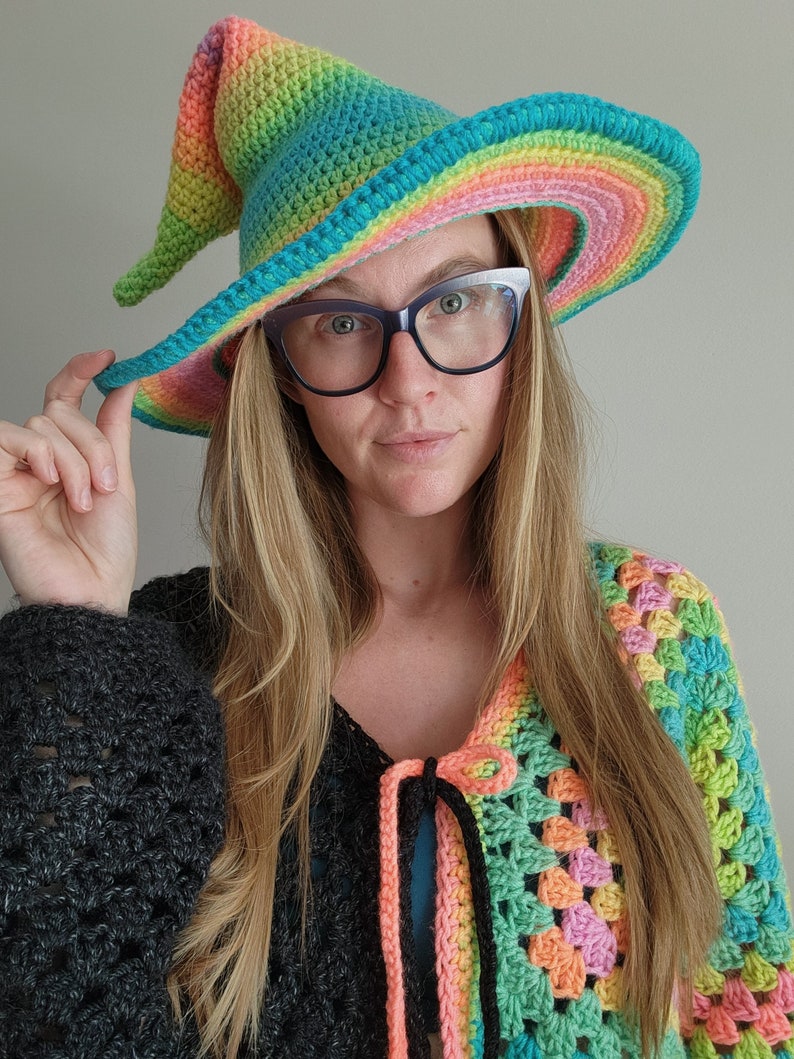 K&ouml;nnte beinhalten: Eine Frau tr&auml;gt einen Regenbogen-H&auml;kelhut und eine mehrfarbige H&auml;keljacke.