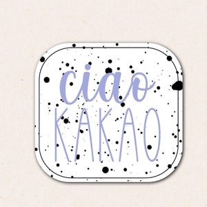 Può includere: Sticker bianco con schizzi di vernice nera e il testo "ciao kakao" in viola.