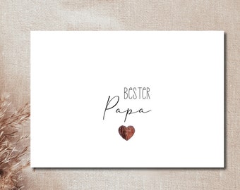 May include: White card with the text "Bester Papa" in black cursive writing and a small brown heart.