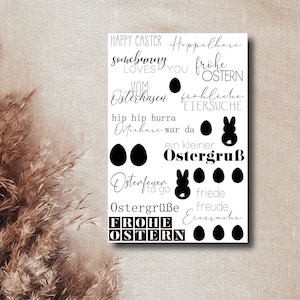 Könnte beinhalten: Eine weiße Karte mit schwarzem Text und Bildern. Der Text enthält Sätze wie "Happy Easter", "Hoppelhase", "Frohe Ostern", "Vom Osterhasen", "Frohliche Eiersuche", "Hip Hip Hurra", "Osterhase war da", "Ein kleiner Ostergruß", "Osterfeuer to go", "Ostergrüße", "Frohe Ostern", "Friede Freude Eiersuche". Die Bilder zeigen Hasen, Eier und andere Ostern-Symbole.