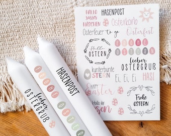 May include: Three white candles with Easter-themed designs. The candles are decorated with pastel pink, green, and brown Easter eggs and the text "Frohe Ostern", "Lieber Ostergrus", and "Hasenpost".