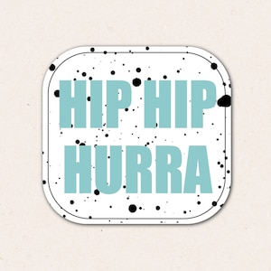 Può includere: Etichetta bianca con schizzi di vernice nera e il testo "HIP HIP HURRA" in azzurro.