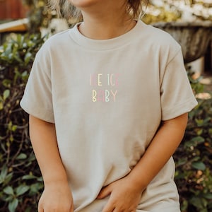 May include: A light beige short-sleeved t-shirt with the text "ICE ICE BABY" in rainbow colors.