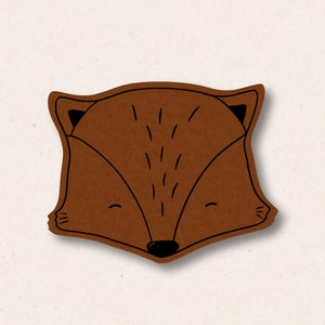 May include: A brown felt fox head with black eyes and a closed mouth. The fox has a simple, cartoon-like design.