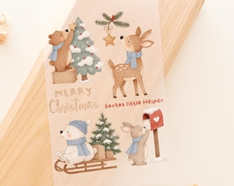 May include: A translucent sticker sheet featuring watercolor illustrations of a brown bear decorating a Christmas tree, a deer, a white bear on a wooden sled, and a rabbit by a mailbox. The text reads Merry Christmas and Santas little Helper.