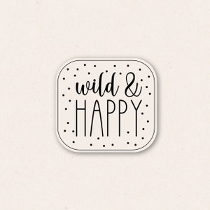 Może przedstawiać: Biała naklejka z czarnymi kropkami i tekstem "wild & happy" w odręcznym stylu.