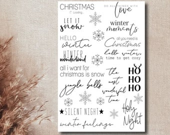 May include: A white rectangular print featuring black text and snowflake graphics. Phrases include "Christmas," "Let it snow," "Hello winter," and "Winter wonderland." Other text includes "Do all things with love," and "Silent Night."