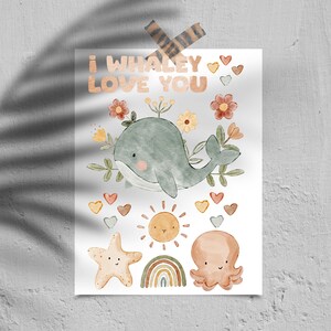 Pode incluir: Uma ilustração em aquarela de uma baleia com o texto "I whaley love you" acima dela. A baleia está cercada por flores, corações, um sol, um arco-íris, uma estrela do mar e um polvo.