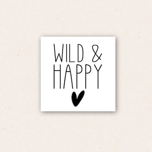 May include: A white card with black text that reads "WILD & HAPPY" with a small black heart below the text.