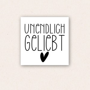 May include: Black and white print with the text "UNENDLICH GELIEBT" and a small heart.