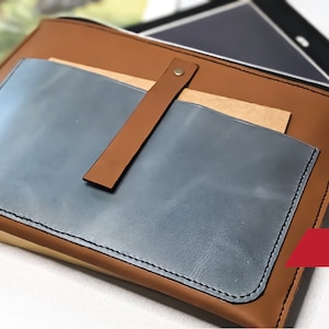 May include: A brown leather tablet sleeve with a blue leather pocket and a brown leather strap. The sleeve has a metal clasp and a brown leather wrist strap. The text "PDF" is visible in the lower right corner of the image.