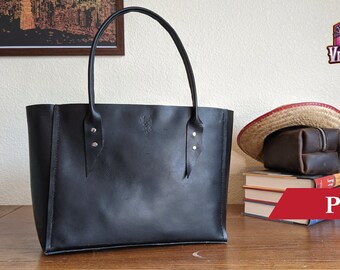 May include: A black leather tote bag with two silver buckles on each side. The bag is sitting on a wooden table. The text "PDF" is in the lower right corner of the image.