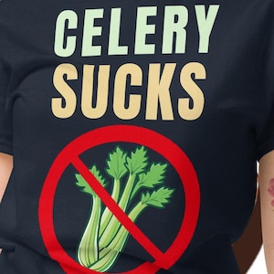 Puede incluir: Una camiseta azul marino con las palabras "CELERY SUCKS" en letras verdes y beige. Un círculo rojo con una línea contiene un tallo de apio verde. El fondo tiene ilustraciones de comida de dibujos animados.