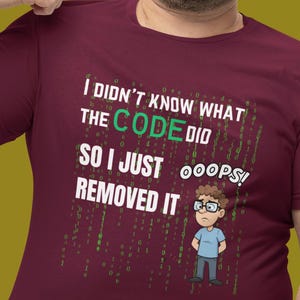 May include: Burgundy t-shirt with the text "I didn't know what the code did so I just removed it" and a cartoon of a person wearing glasses. The shirt has a round neck and short sleeves.