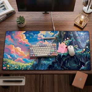May include: A large rectangular desk mat featuring a vibrant illustration of a pink creature sitting on a grassy cliffside near a cave, with a colorful sunset sky filled with stars, a mechanical keyboard, and a white computer mouse on top.