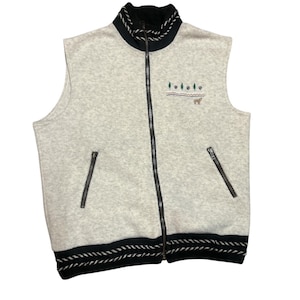 May include: A light gray fleece vest with a full-length black zipper and two side pockets. The vest has black and white rope trim on the collar and hem. An embroidered design of trees, paw prints, and a bear is on the chest.