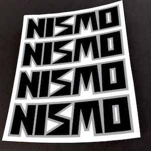 May include: Four black and white NISMO stickers on a white sheet of paper. The stickers are arranged in a vertical stack.