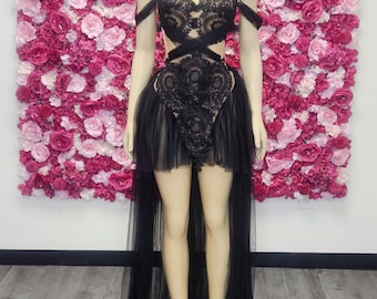 Könnte beinhalten: Schwarzes Spitzen- und Tüllkleid auf einer Schaufensterpuppe. Das Kleid hat ein schulterfreies Design mit aufwendigen Spitzendetails am Oberteil und einem fließenden Tüllrock. Das Kleid hat einen High-Low-Saum mit einer längeren Schleppe hinten.