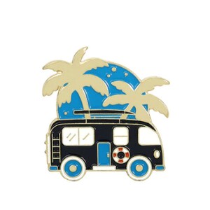 May include: Black and gold enamel pin featuring a vintage camper van with a surfboard on the roof, palm trees, and a blue and white sunset.