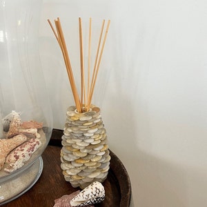 May include: A diffuser made of stacked stones in shades of gray and beige with natural wooden sticks protruding from the top.