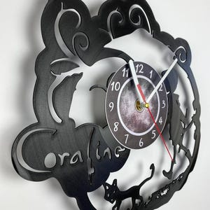 Puede incluir: Reloj de vinilo negro con una silueta de Coraline y la Otra Madre de la pel&iacute;cula Coraline. La esfera del reloj es un c&iacute;rculo blanco con n&uacute;meros y manecillas negros.