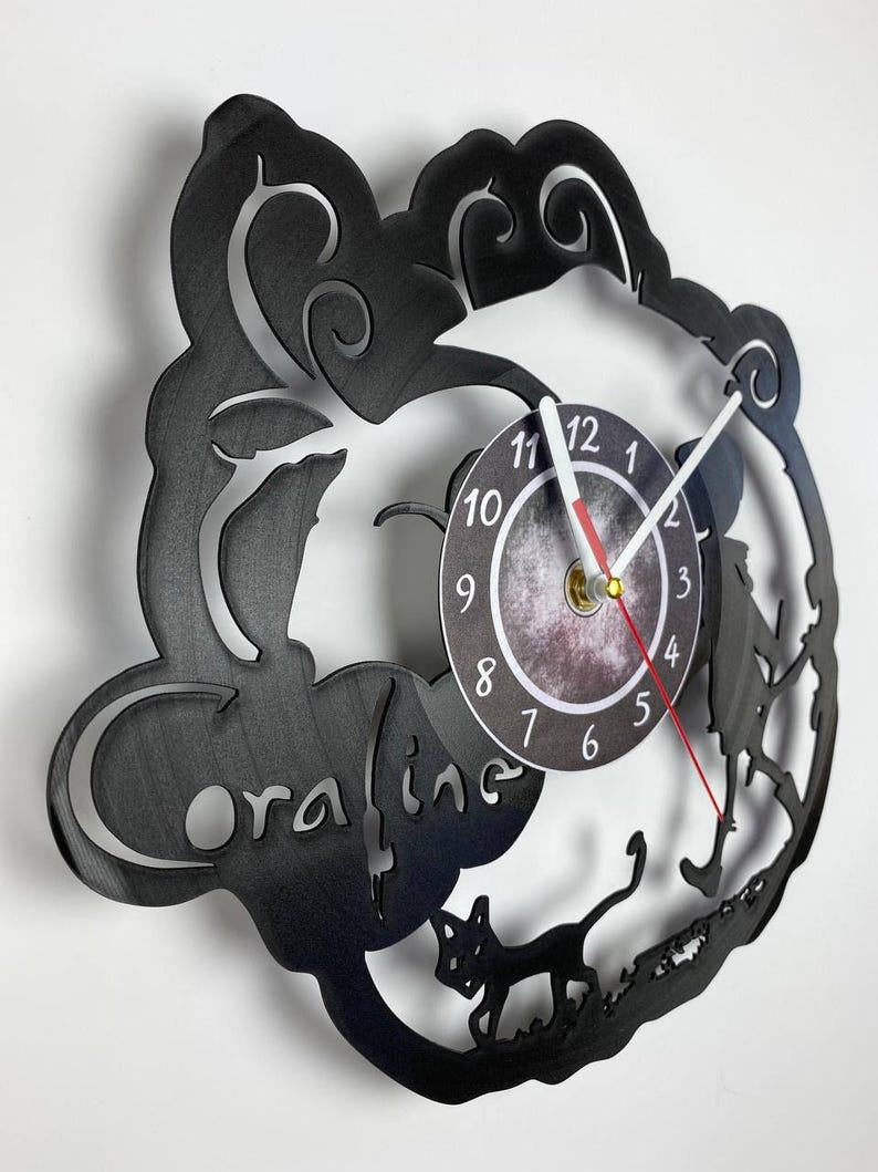 Puede incluir: Reloj de vinilo negro con una silueta de Coraline y la Otra Madre de la pel&iacute;cula Coraline. La esfera del reloj es un c&iacute;rculo blanco con n&uacute;meros y manecillas negros.
