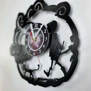 Puede incluir: Reloj de vinilo negro con una silueta de una persona paseando un gato. La esfera del reloj es blanca con n&uacute;meros y manecillas negros.
